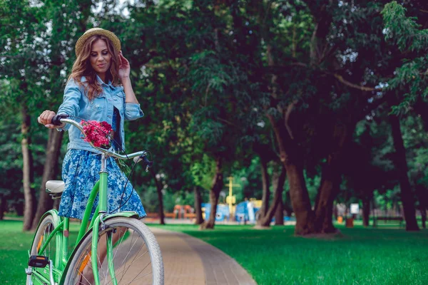 Retrato de feliz sorridente jovem montando uma bicicleta no parque . — Fotografia de Stock