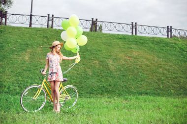 Güzel genç kadın bir yeşil çim zemin üzerine bir bisiklet üzerinde.