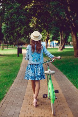 Güzel bir kadının arka görünümünden bir retro bisiklet ile gidiyor.