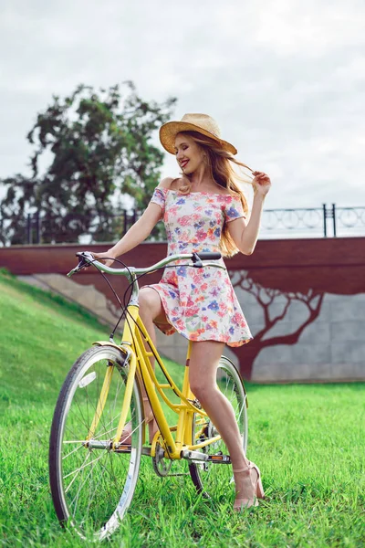 Mulher bonita nova com bicicleta amarela em um parque . — Fotografia de Stock