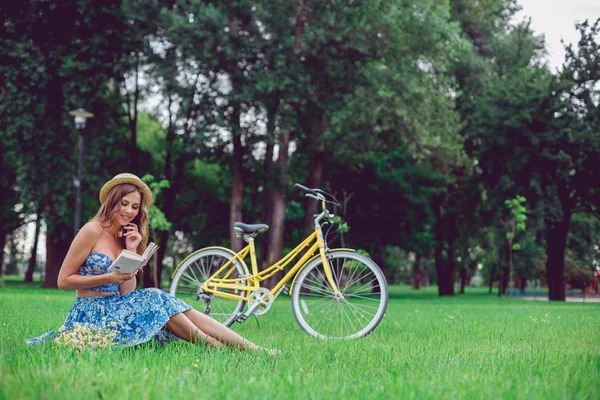 Jovem mulher relaxando em uma grama verde com bicicleta em um parque em um dia ensolarado . — Fotografia de Stock