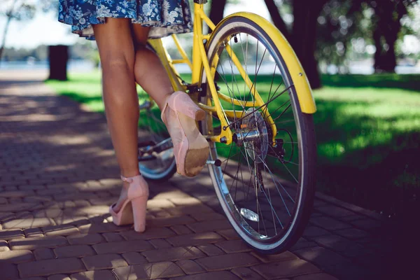 Close-up de pernas femininas em botas de verão e roda retro de bicicleta amarela — Fotografia de Stock