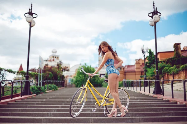 Mulher incrível posando perto de bicicleta, modelo de moda em roupas sexy . — Fotografia de Stock