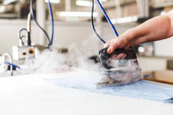 Professional ironing in dry cleaner detail of iron and hands