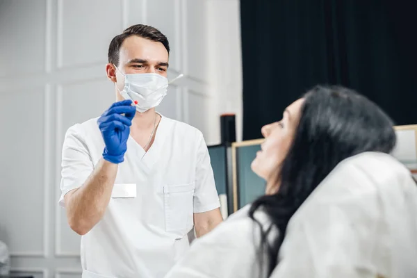 Médico masculino usando um cotonete para tirar uma amostra de uma garganta de pacientes — Fotografia de Stock