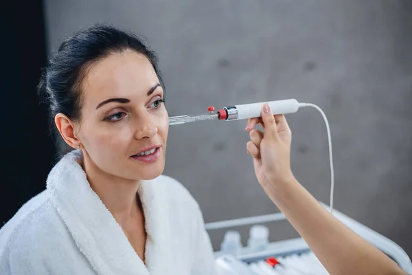 Läkare kosmetolog bedriver diagnostik av ett villkor för en hud i ansiktet av patienten. — Stockfoto