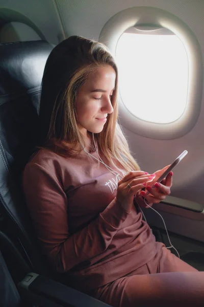 Tjej läser från smartphone i flygplan — Stockfoto
