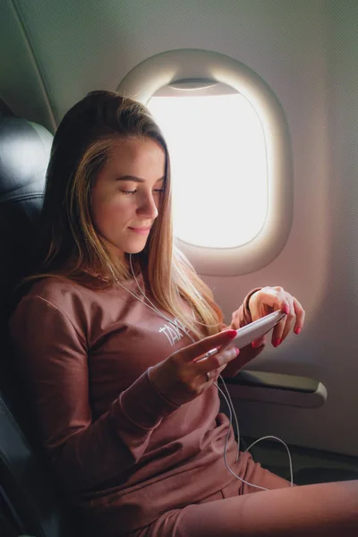 Девушка читает со смартфона в самолете — стоковое фото