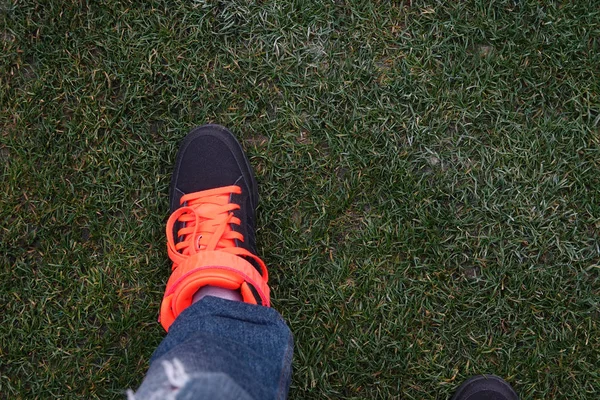 Male leg in black sneakers on a green lawn. — Stock Photo, Image