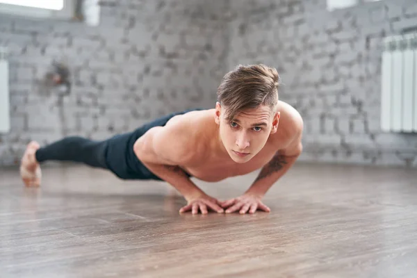 Lekkoatletycznego młody człowiek robi push up na podłodze — Zdjęcie stockowe