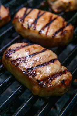 Izgarada pişirilmiş domuz pirzolası ve ballı barbekü sosu.