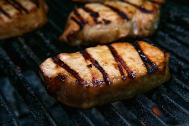 Izgarada pişirilmiş domuz pirzolası ve ballı barbekü sosu.