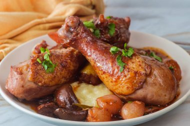 Fransız mutfağı Coq Au Vin güveci, mantarlı incili soğan ve patates püresi üzerine servis edilen kırmızı şarap brendisi soslu havuç.