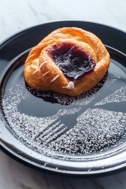 Böğürtlenli kremalı ve pudra şekerli Danimarka çöreği.