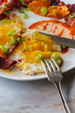 Güneşli tarafı yumurtalı Amerikan kahvaltısı pastırmalı tatlı patates pancar cipsi ve acı sos.