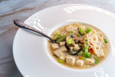 Bir kase dolusu Japon miso çorbası erişteli tofu jülyen havuç ve kabak.