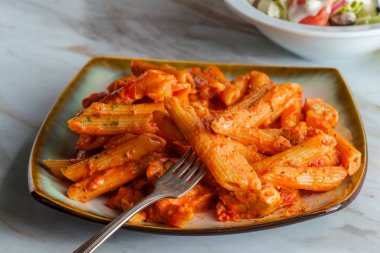 Kremalı votka soslu İtalyan makarna ve mermer mutfak masasında ızgara tavuk.