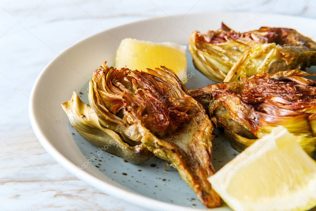 Italian fried halved artichoke with lemon wedges