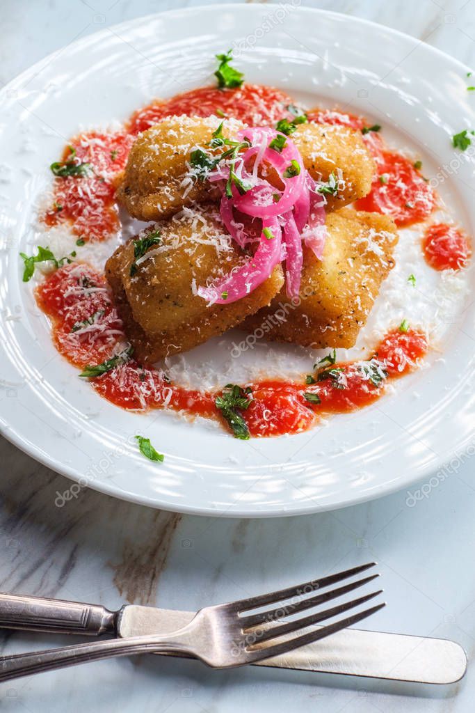 Breaded fried Italian ravioli topped with pickled red onions and grated pecorino romano cheese and hot marinara tomato sauce