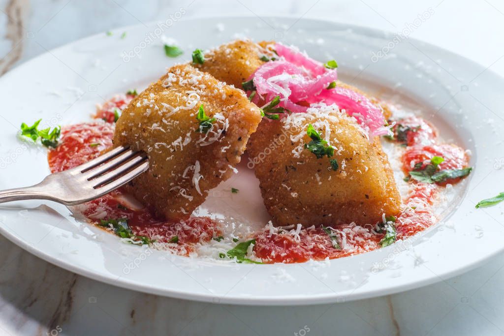 Raviolis italianos fritos rematados con cebollas rojas en escabeche y