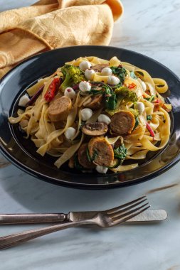 Sarımsaklı beyaz şarap soslu İtalyan tavuğu fettuccine primavera brokoli mantarlı bebek lahana, kurutulmuş domates ve küçük perline mozzarella.