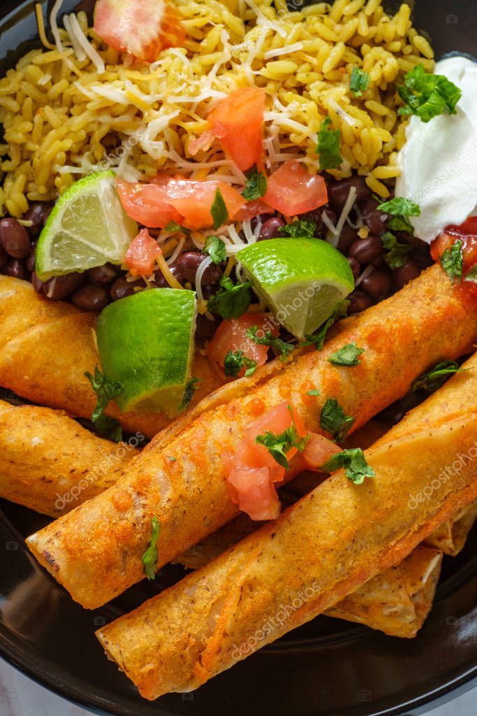 Taquitos mexicanos de pollo y queso con arroz y frijoles negros 2024