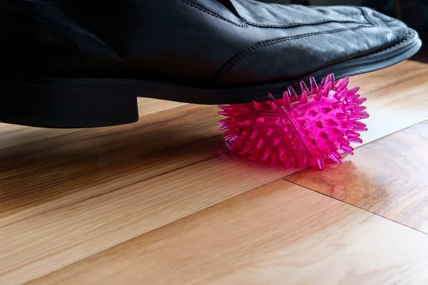 Shoe stepping on and squashing coronavirus cell as metaphor for finding the cure or vaccine