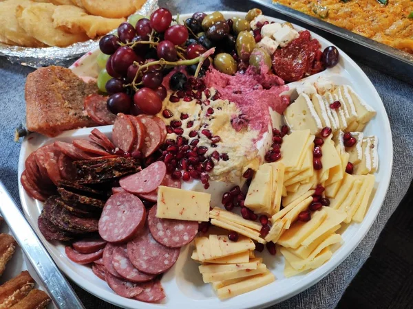 Delicious cheese board with gouda cheese salami ham italian smoked slices of salami grape olive sauce on white plate gourmet assortment of cheese