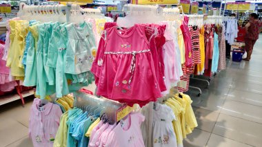 Saigon/Vietnam - Dec 01, 2019: Variety of beautiful baby girl dresses on stands and hangers in supermarket. Clothes for little girls, cotton dresses from nature fabrics asian child girl fashion store.
