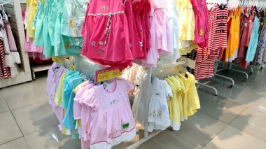 Saigon/Vietnam - Dec 01, 2019: Variety of beautiful baby girl dresses on stands and hangers in supermarket. Clothes for little girls, cotton dresses from nature fabrics asian child girl fashion store.