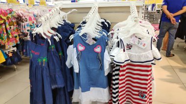 Saigon/Vietnam - Dec 01, 2019: Variety of beautiful baby girl dresses on stands and hangers in supermarket. Clothes for little girls, cotton dresses from nature fabrics asian child girl fashion store.