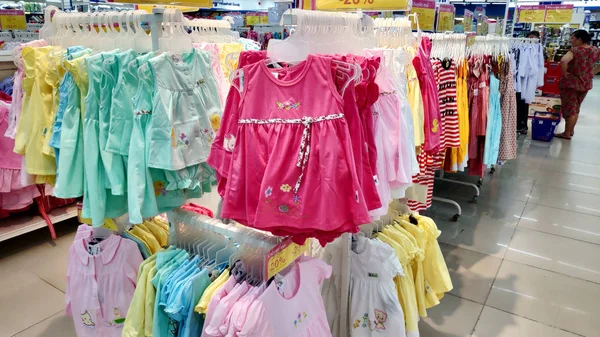 Saigon/Vietnam - Dec 01, 2019: Variety of beautiful baby girl dresses on stands and hangers in supermarket. Clothes for little girls, cotton dresses from nature fabrics asian child girl fashion store.