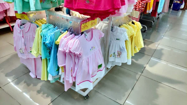 Saigon/Vietnam - Dec 01, 2019: Variety of beautiful baby girl dresses on stands and hangers in supermarket. Clothes for little girls, cotton dresses from nature fabrics asian child girl fashion store.