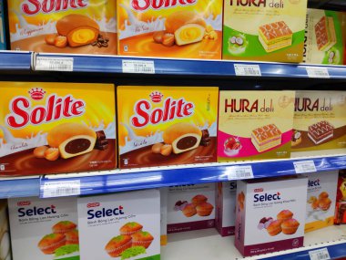Saigon / Vietnam - July 01 2019: Boxed cakes and biscuits on supermarket shelves. Assorted boxes of branded cake flours. A grocery store shelf with baking: Orion Choco-Pie, Solite, Goute, LU, Custas