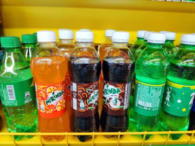 Karbonatlı içecekler tatlı su, içecek çayı krema ve şekerle karıştırılmış kahve suyu süpermarketteki raflarda sergilenen çeşitli içki şişeleri ve kutular..