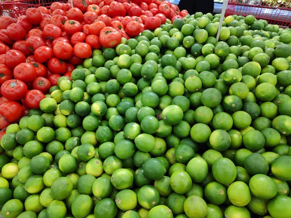Süpermarkette sebzeler sergileniyor. Markette yeşil limonlu sepetler ve kırmızı domates var. Manav. Taze sebzeler ve meyveler. Meyve kutuları.