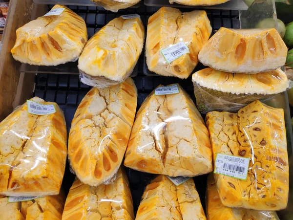Süpermarketteki rafta plastik film sergilenen taze Jackfruit. Markette sarı olgun meyvelerin yarısı var. Yemek için doğal iyi vitamin ürünleri.