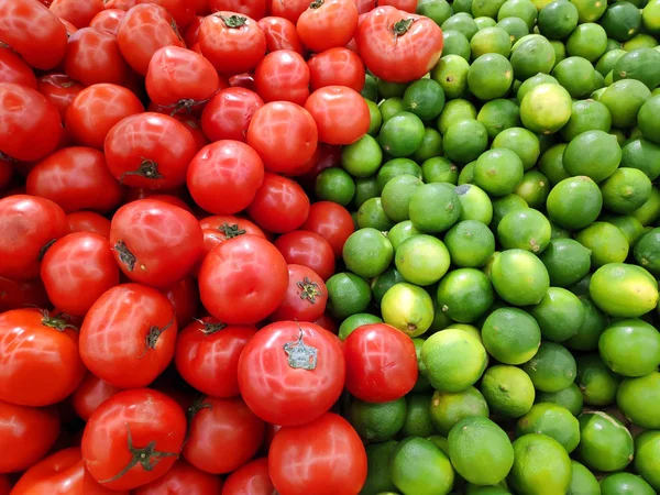 Süpermarkette sebzeler sergileniyor. Markette yeşil limonlu sepetler ve kırmızı domates var. Manav. Taze sebzeler ve meyveler. Meyve kutuları.
