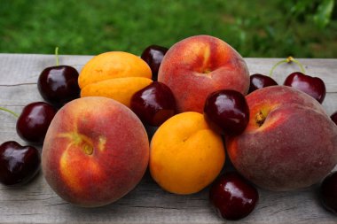 Yaz meyveleri, kayısı, kayısı, şeftali, ahşap masa, yeşil çimen, sağlıklı yiyecek, meyve, meyve suyu. Otago Yeni Zelanda 'da yeni Zelanda meyvesi, C vitamini, vişne aromalı. 