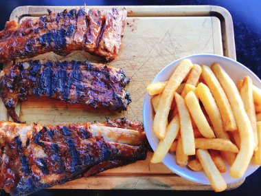 Izgara soslu domuz pirzolası bbq sosu ve kızarmış patates cipsi sosis limonlu kalamar kalamarı ahşap tahtada mayonez mantarlı biber soslu. 