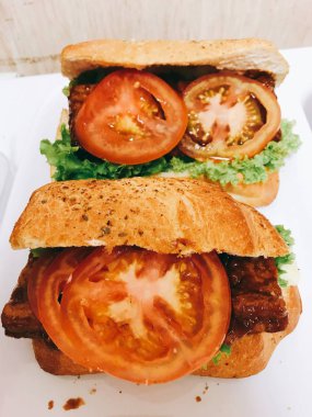 Lezzetli jambon ve peynirli kruvasan, yeşil salata, kırmızı domates dilimleri, rengarenk dekorasyon, sağlıklı kahvaltı, ev yapımı hamur işi sandviç. 