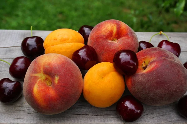 Yaz meyveleri, kayısı, kayısı, şeftali, ahşap masa, yeşil çimen, sağlıklı yiyecek, meyve, meyve suyu. Otago Yeni Zelanda 'da yeni Zelanda meyvesi, C vitamini, vişne aromalı. 