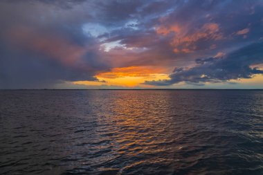 Deniz üstünde mavi bulutlu gökyüzü ile renkli gün batımı. Gevşeme manzara