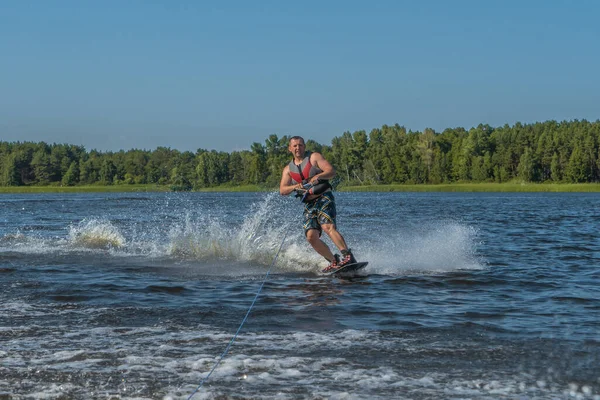 Tense man wakeboarding in a lake and pulled by a boat