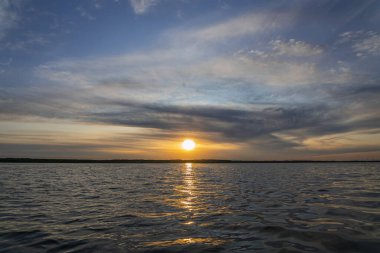 Deniz üstünde mavi bulutlu gökyüzü ile renkli gün batımı. Gevşeme manzara