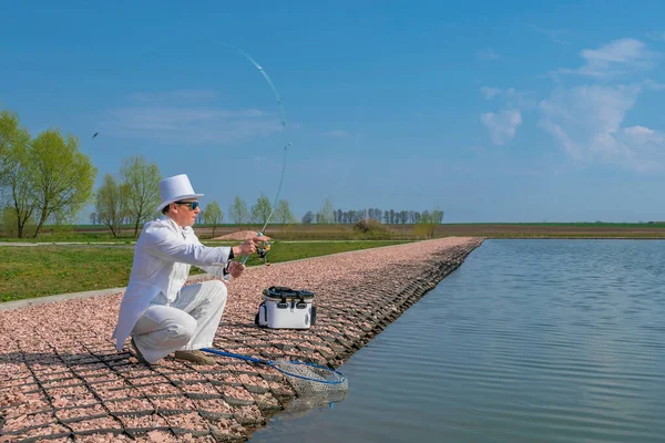 絶妙な釣り 白いスーツの漁師は湖でロッドを回すことによって魚をキャッチ — ストック写真