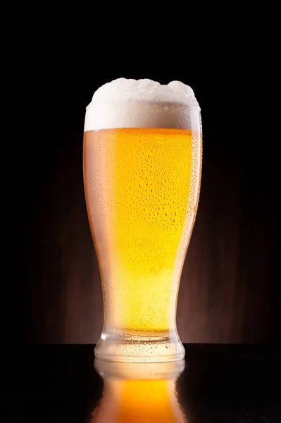 暗い背景の木に冷ややかなガラスの軽いビール — ストック写真
