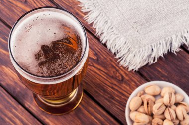 bardak hafif soğuk köpüklü bira, fındık, bez, eski ahşap masa