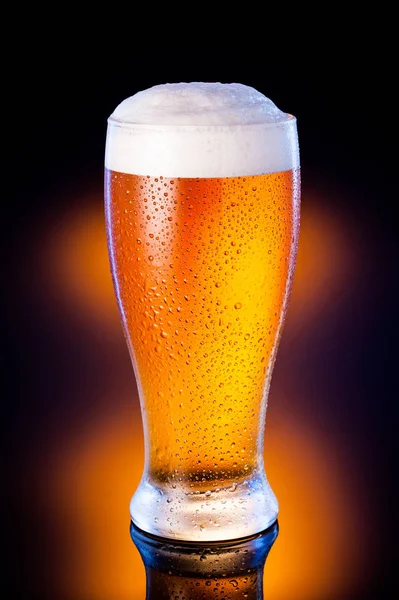 暗い黄色の背景に冷ややかなガラスの軽いビール — ストック写真