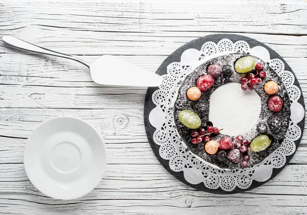 chocolate berry cake on plate over white wooden background
